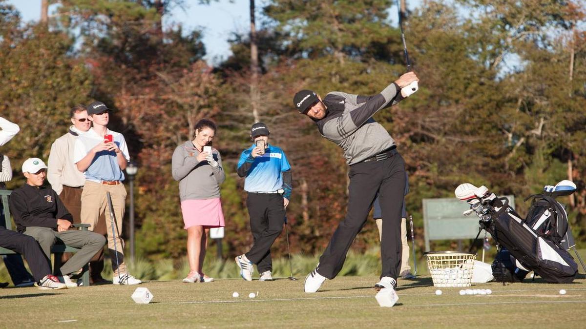 Pro golfer and CCU alumnus Dustin Johnson (left) hits a drive in front of some students from his golf school at TPC Myrtle Beach.