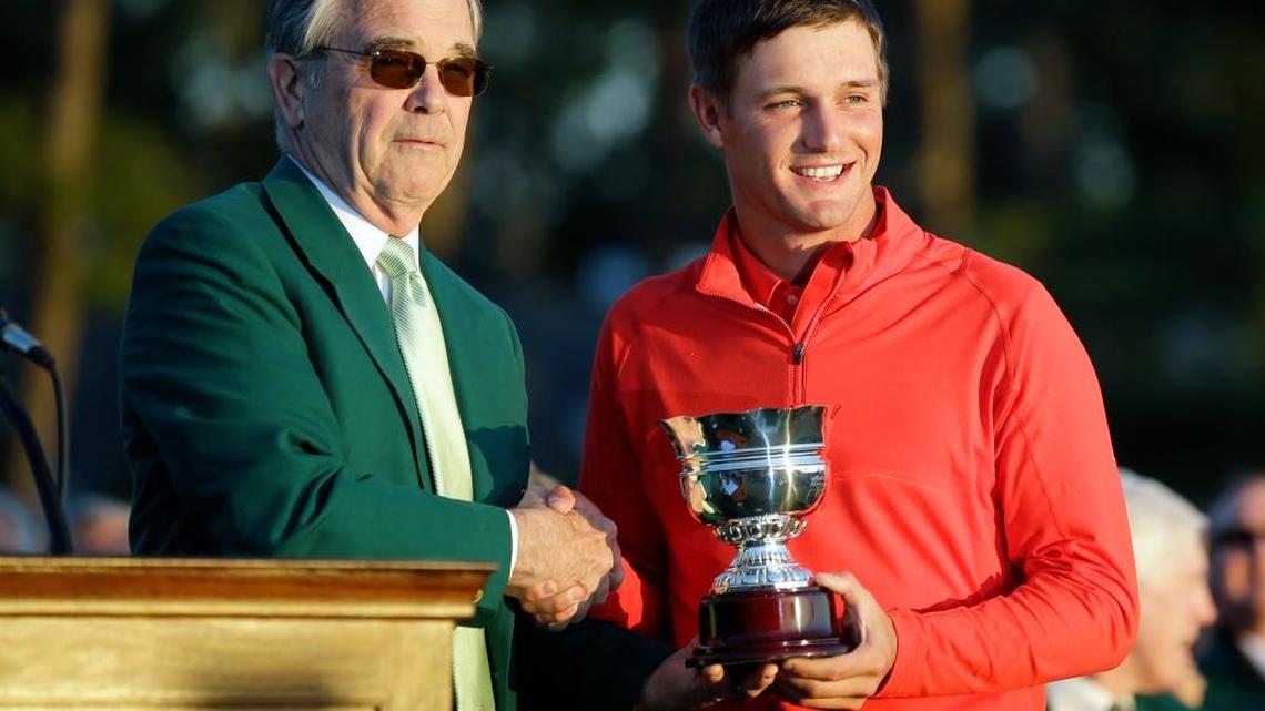 Masters top amateur Bryson DeChambeau is presented with his trophy by Billy Payne, chairman of Augusta National Golf Course, following the Masters.
