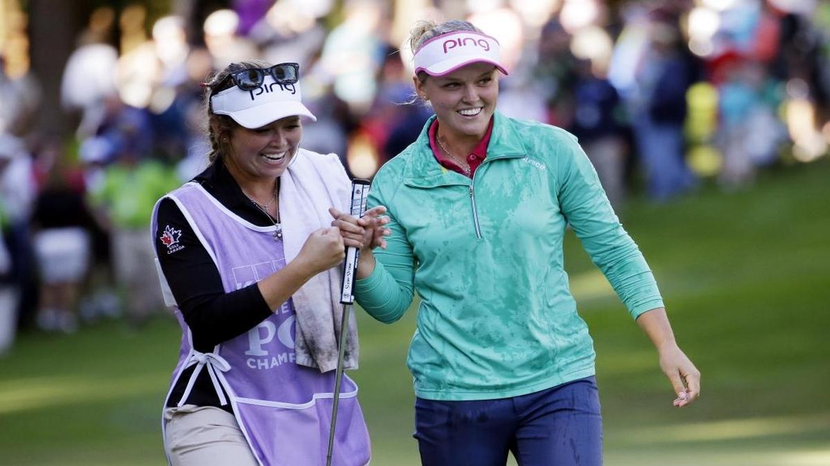 Brooke Henderson, right, walks off the 18th green with her sister and caddie Brittany Henderson after winning the Women’s PGA Championship at Sahalee Country Club on June 12