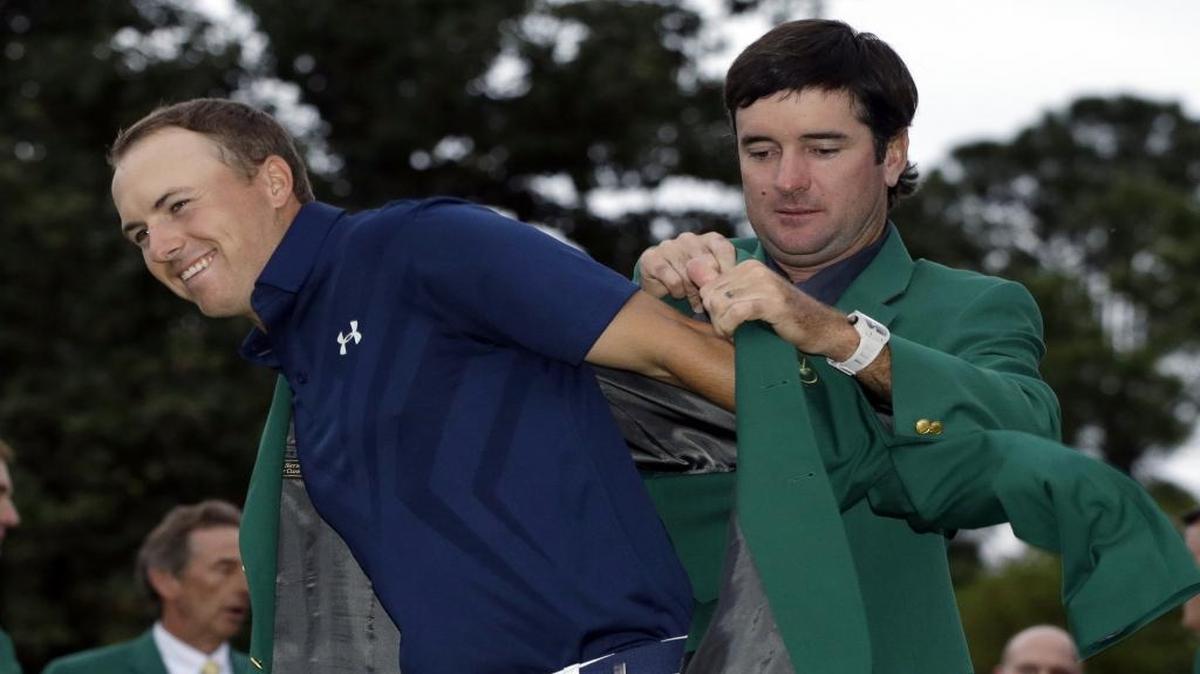 Bubba Watson, right, helps Jordan Spieth put on his green jacket following last year’s Masters win. Spieth will begin his quest for a second consecutive win at the Masters when the tournament starts on Thursday.