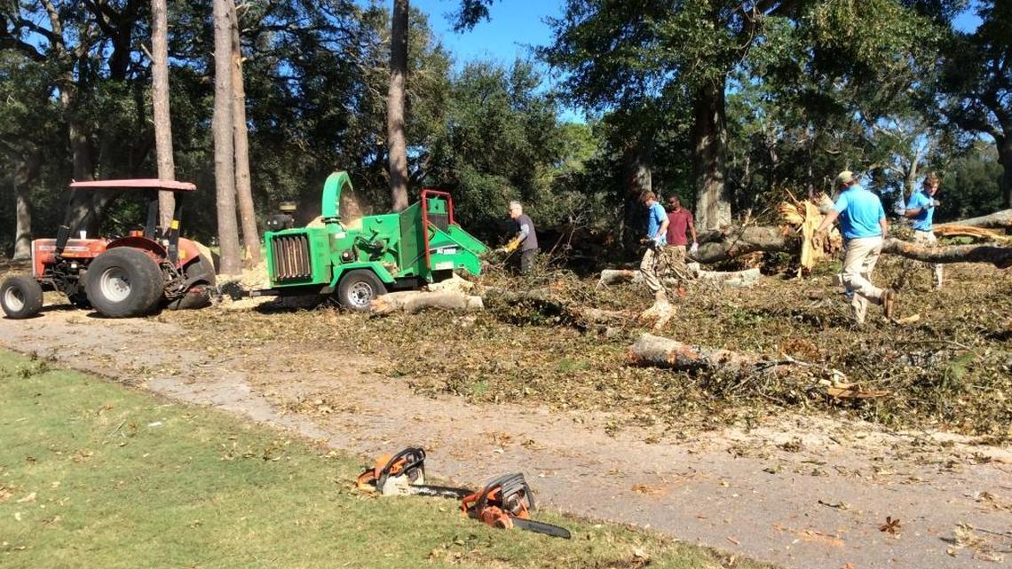 The Dunes Golf and Beach Club head pro Dennis Nicholl loads downed tree branches and limbs to the left of the seventh green into a wood chipper Monday in preparation for the course’s reopening Tuesday.