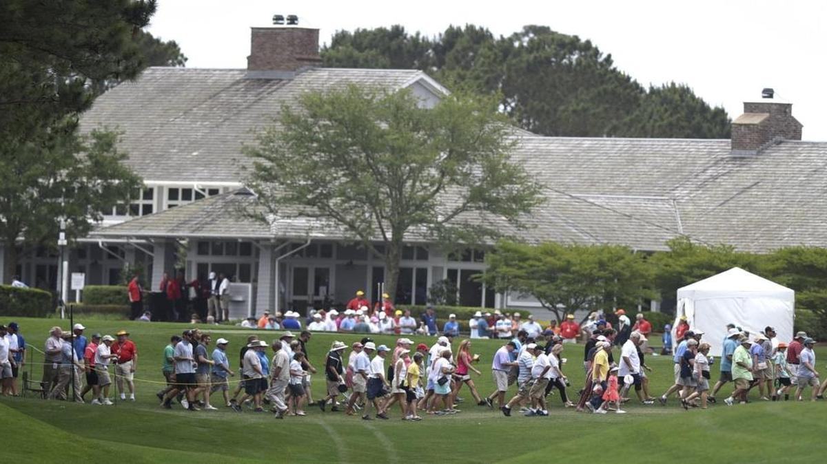 Spectators cross the first hole with the Eagle Point Golf Club clubhouse in the background during a Wells Fargo Championship pro-am on Monday in Wilmington, N.C.