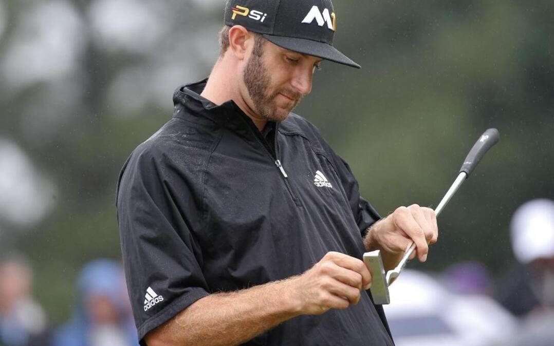 
Dustin Johnson cleans his putter on the first green during the second round of the Tour Championship.
