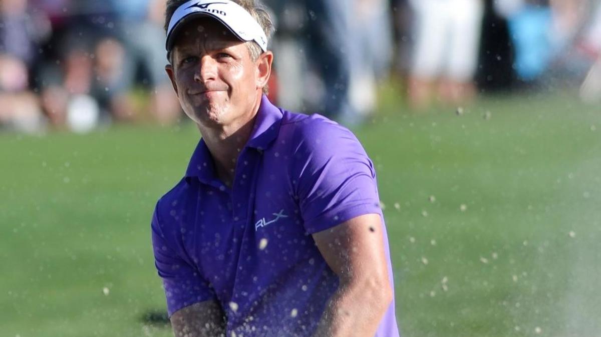 Luke Donald looks through the flying sand after hitting out of a bunker on the 18th hole during the final round of the RBC Heritage.