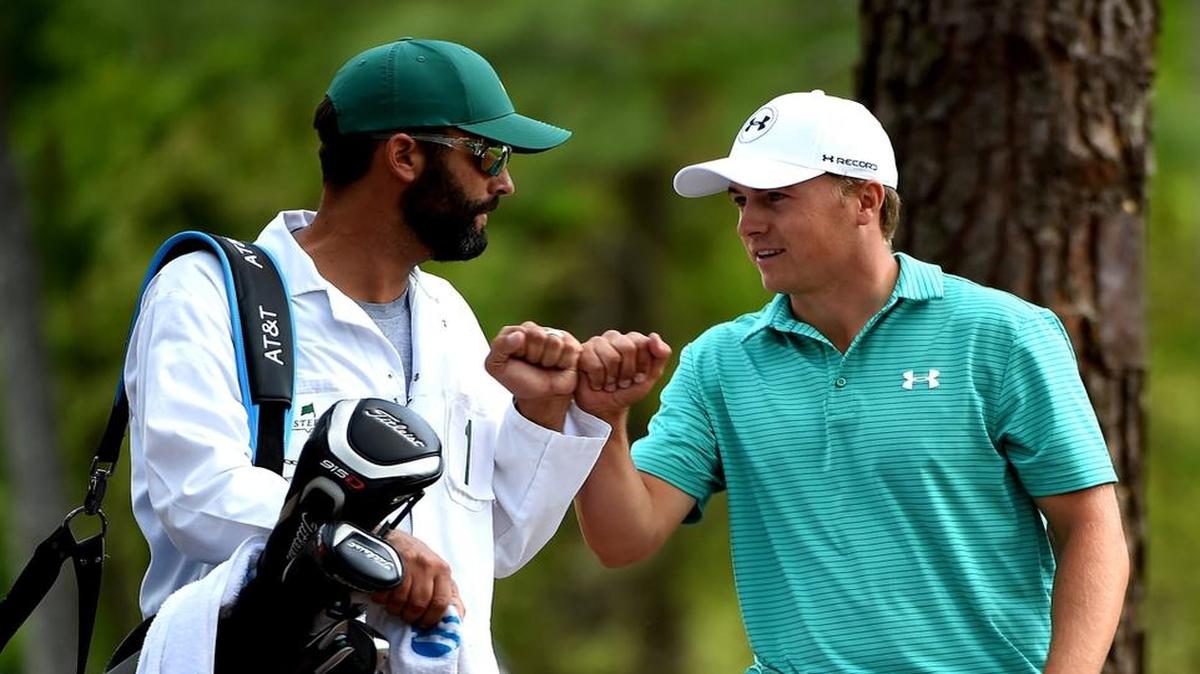 Jordan Spieth, right, bumps fists with his caddie, Michael Greller, after Spieth hit his ball from the rough along the 11th fairway onto the green during the first round of the Masters.