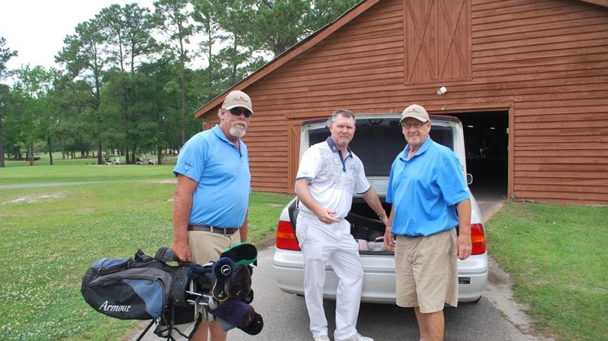 Matt Palmer (left), Shawn Denney and David Marr (right) of Meadowlands Golf Club load clubs for delivery to Fort Bragg.