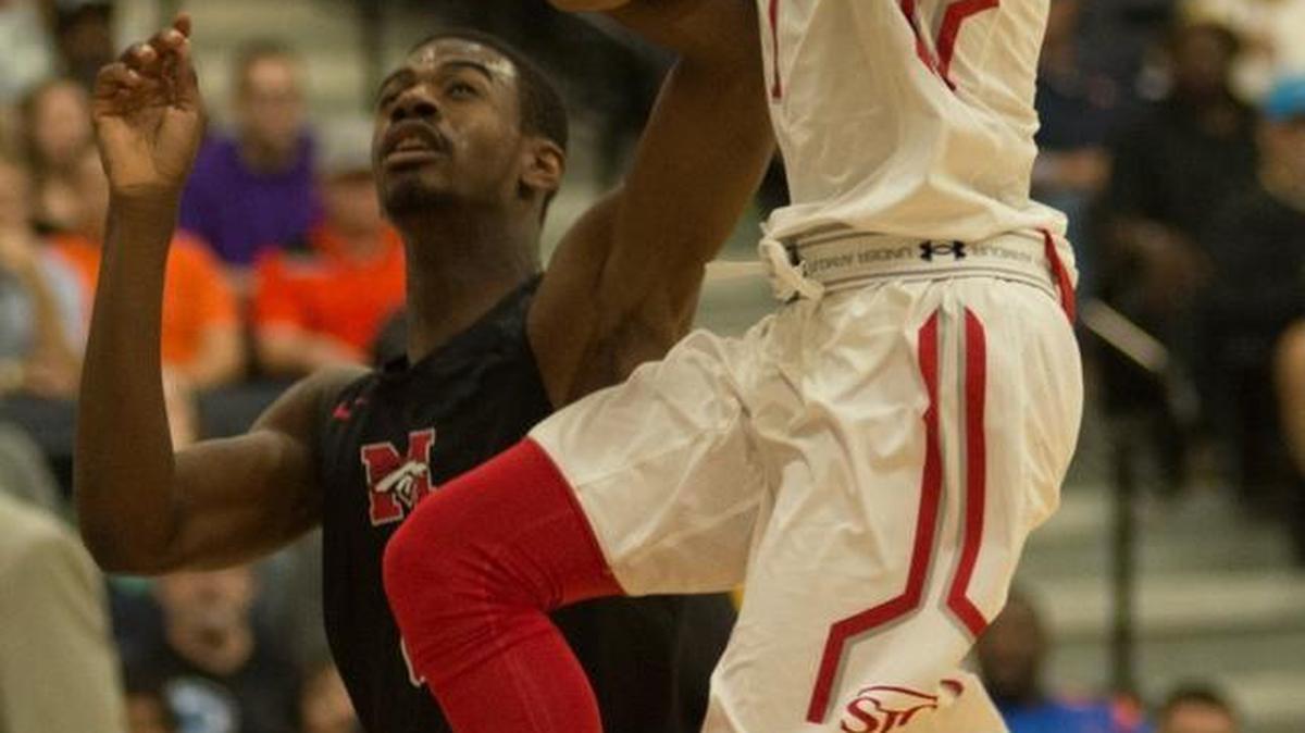 St John’s senior Anthony Cowan Jr. (with ball) goes up for a shot over a Mustang defender.