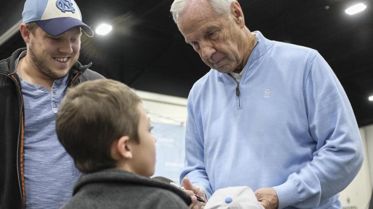 University of North Carolina basketball coach Roy Williams signs a hat for 7-year-old Ayden Kerley of Taylorsville, N.C. at the 2017 Beach Ball Classic in Myrtle Beach on Thursday.