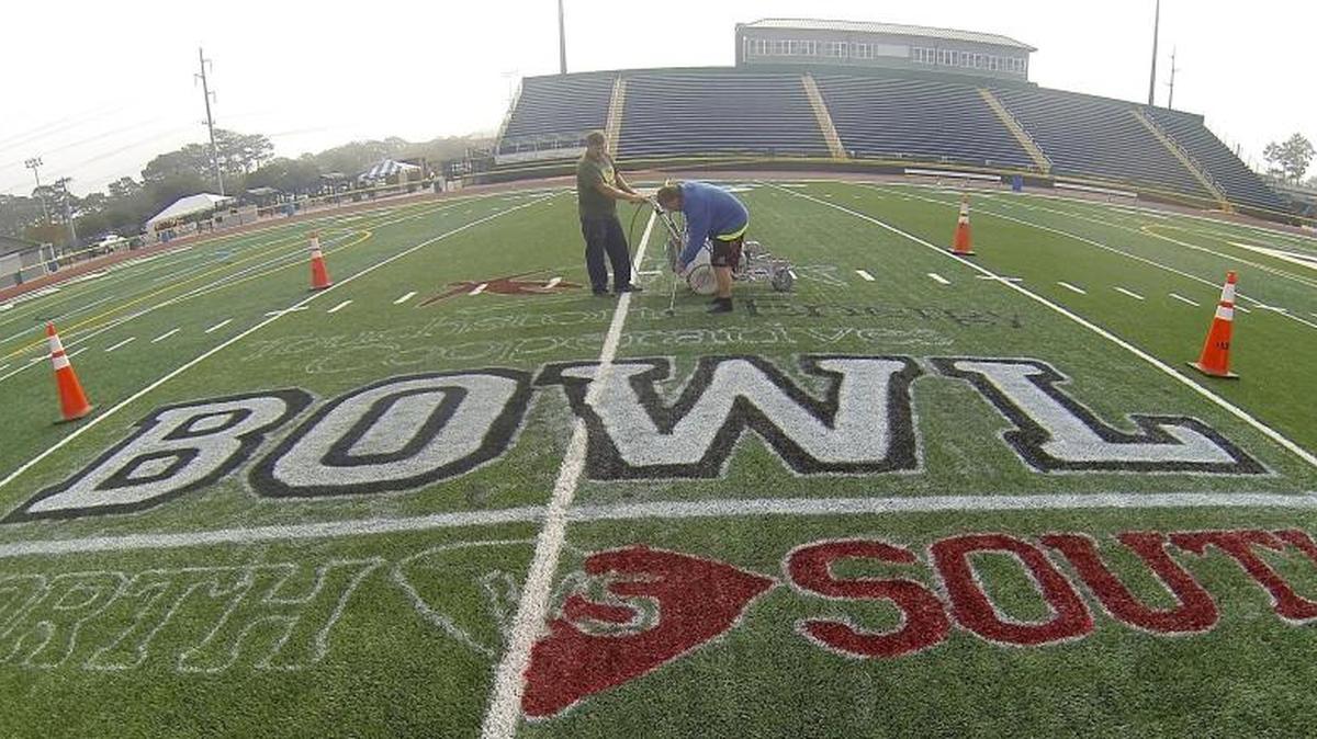 Paint crews prepare field logos for Saturday’s Touchstone Energy Cooperatives North-South Bowl at Doug Shaw Memorial Stadium.
