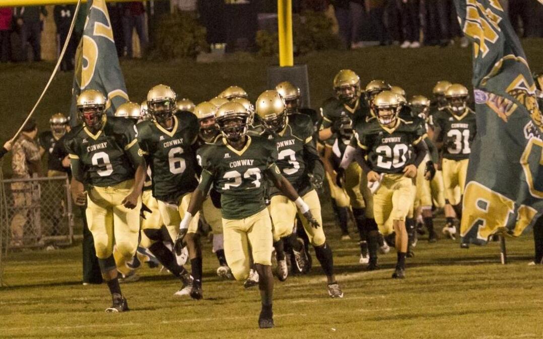 The Conway High football team hits the field before a game last season.