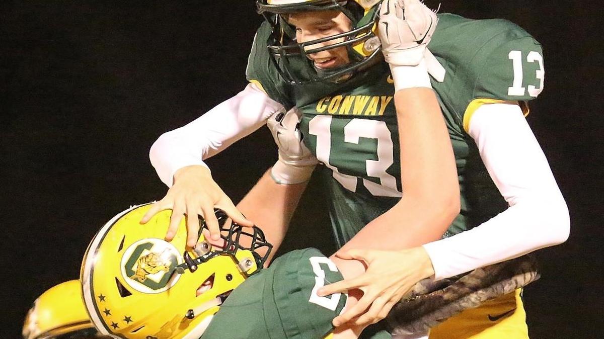 Conway offensive lineman Gunner Britton lifts quarterback Peyton Derrick following a touchdown this past season.