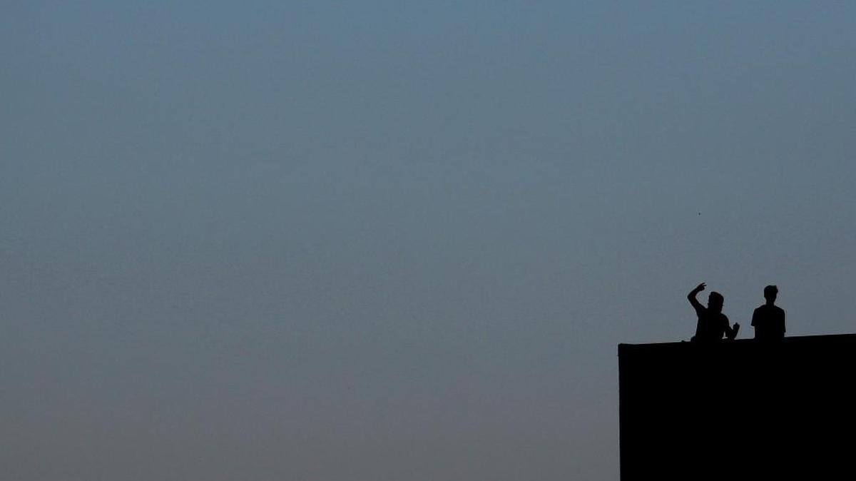Two people cheer from the top of the school during Monday’s game.