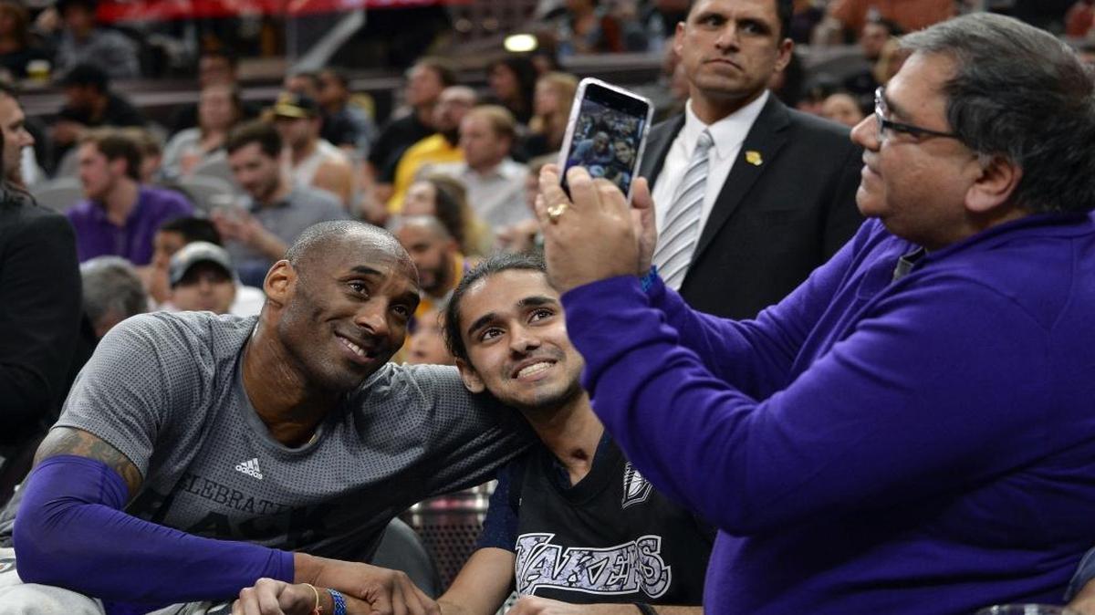Los Angeles Lakers guard Kobe Bryant, left, poses for a photo with a fan during the first half of Saturday’s game against the San Antonio Spurs.