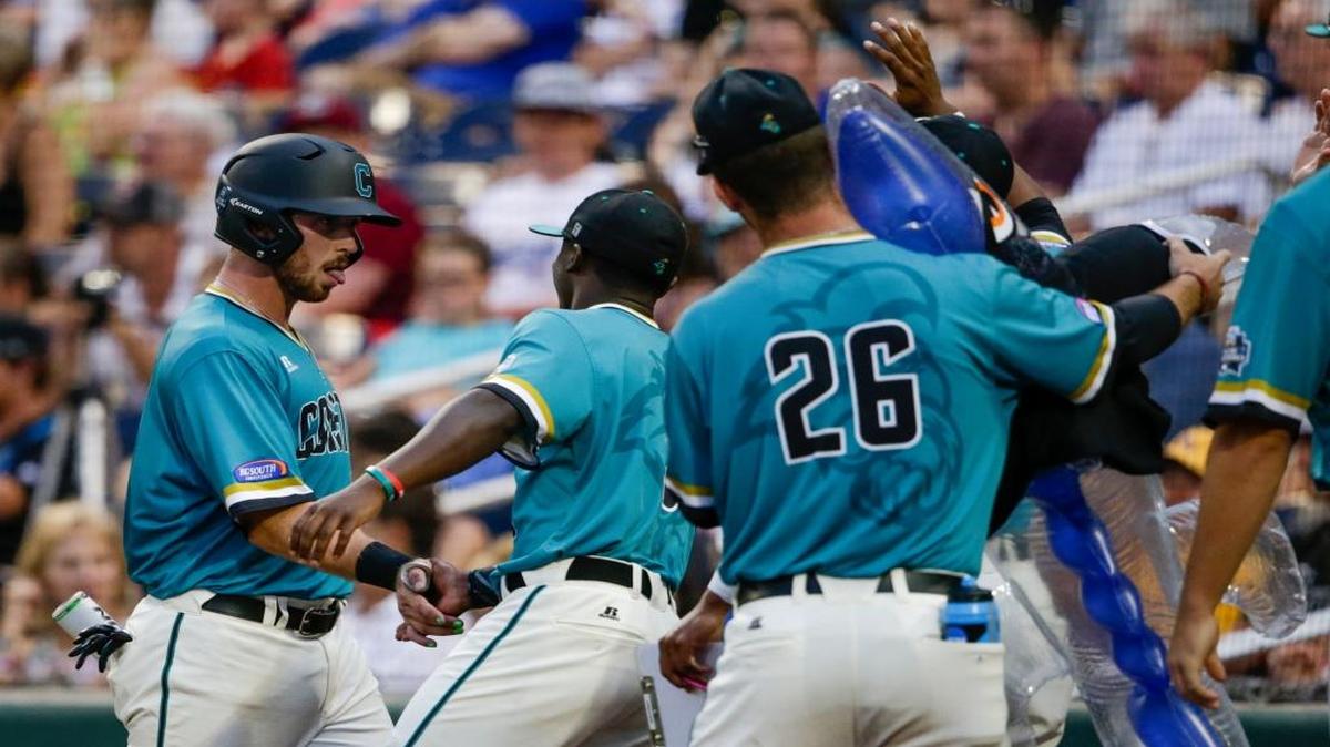 Coastal Carolina’s David Parrett, left, is greeted by teammates, including Seth Lancaster (26) , holding an inflatable shark, after scoring against TCU on a single by Zach Remillard during the fourth inning Saturday.