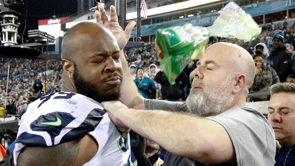 A Seattle staff member tries to remove Seahawks defensive tackle Quinton Jefferson, left, from the field as an object thrown from the stands hits them during the closing moments of Sunday’s game against the Jacksonville Jaguars.