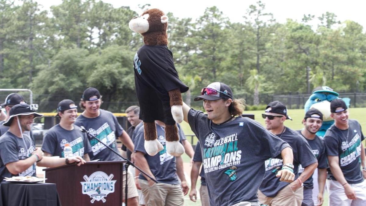 Coastal Carolina’s Bobby Holmes gets the crowd excited by running around the infield with Rafiki the Rally Monkey during a celebration at Springs Brooks Stadium.