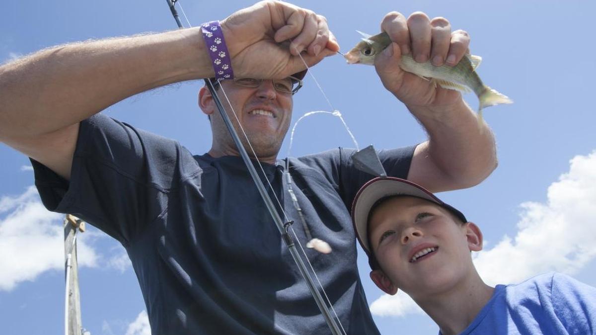 Brent McCord unhooks a pin fish for his son Jacob during a family fishing trip to Cherry Grove pier on Saturday. McCord, together with his brother-in-law, Adam DeLange, took their four children fishing during the Father's Day Weekend.