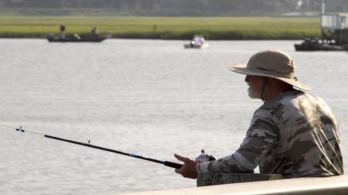 Nelson Hartline from Trenton, Ga., fishes from the Cherry Grove causeway last year as boats troll the inlet.