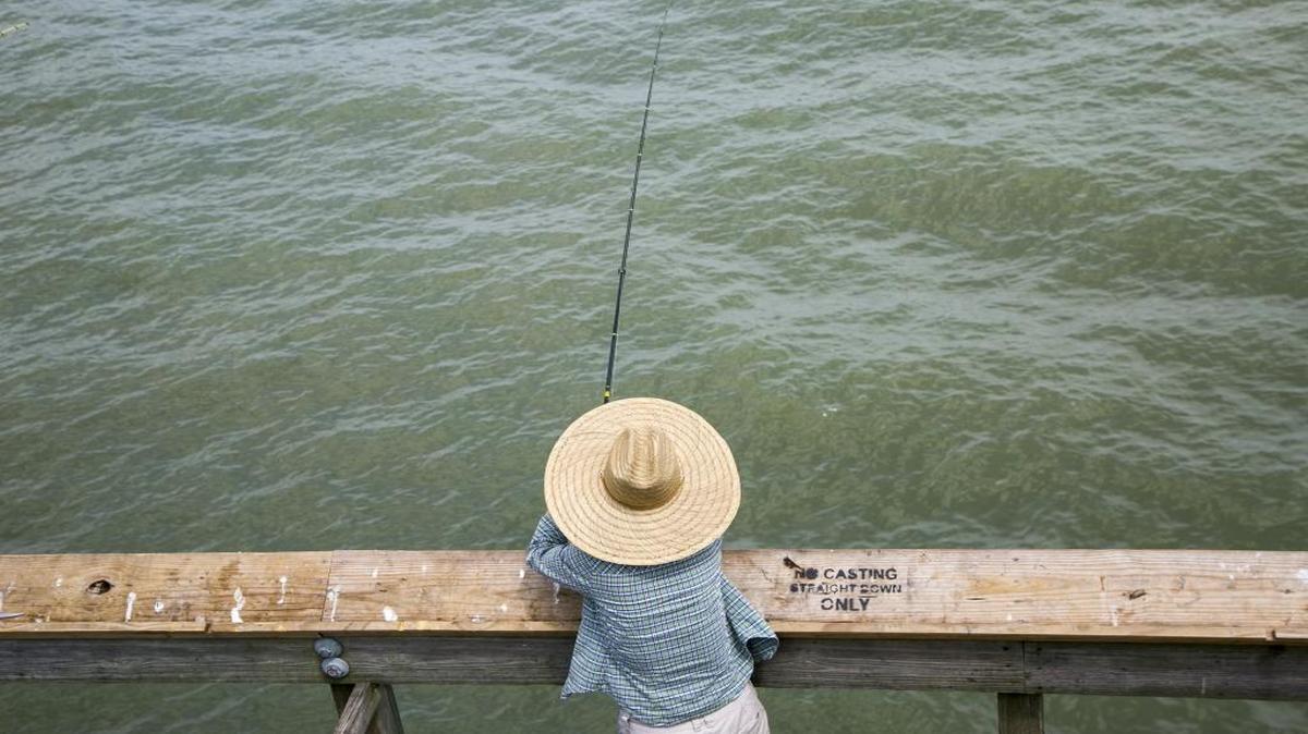 Sun Kim of Fayetteville, N.C., fishes under a big hat on the Apache Pier last year.