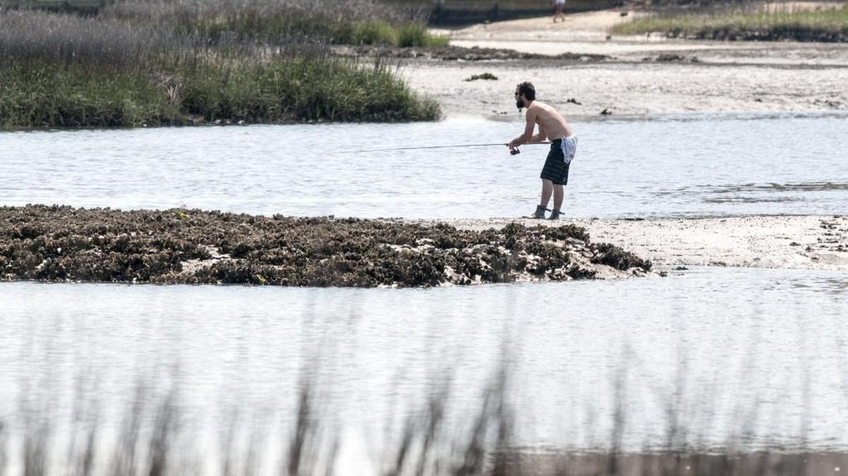 A fisherman walks the oyster bars at low tide in Cherry Grove Inlet in North Myrtle Beach.