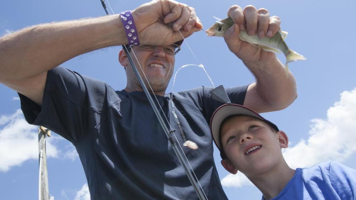Brent McCord unhooks a pin fish for his son Jacob during a family fishing trip to Cherry Grove pier.