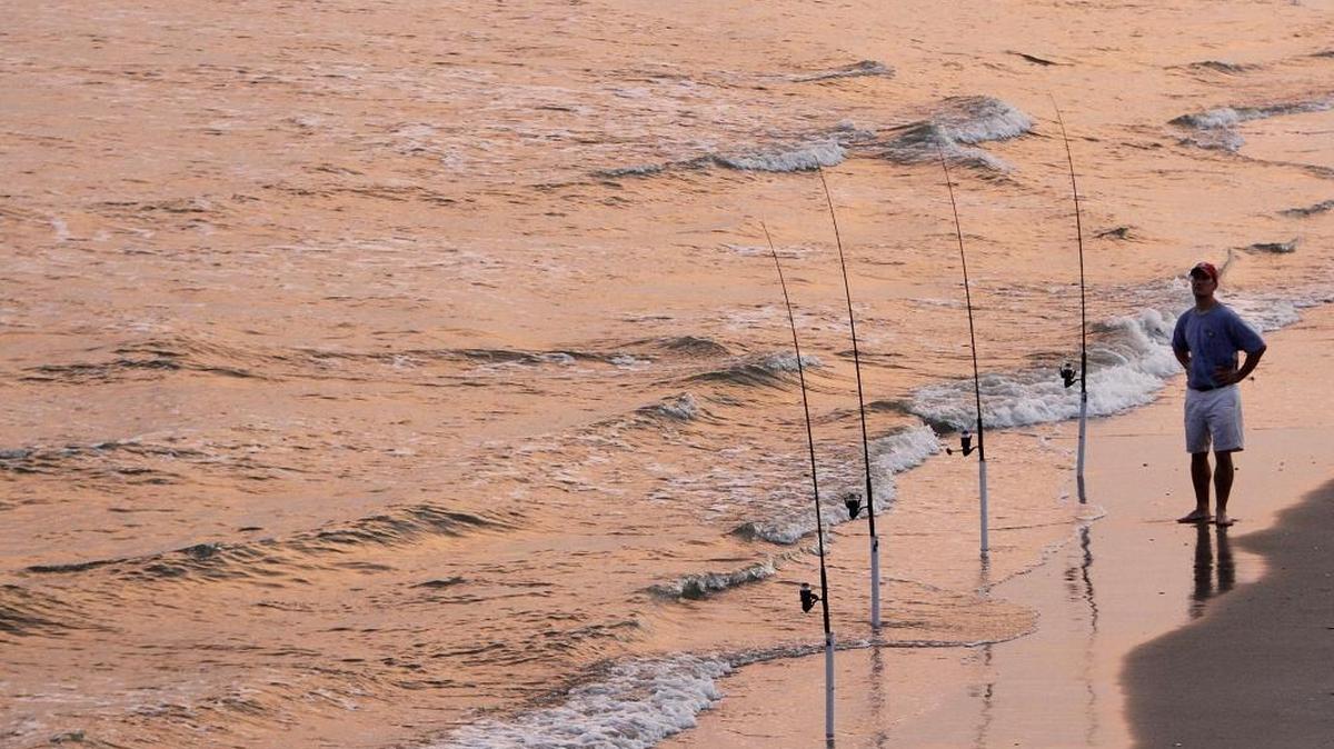 A fisherman waits for a bite as the sun sets in Garden City Beach.