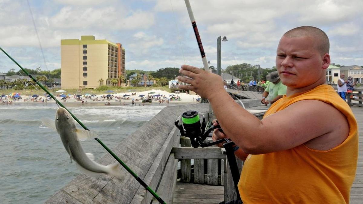 Robert Taylor of Greenville, Tenn., catches a whiting while fishing on the Surfside Pier last year.